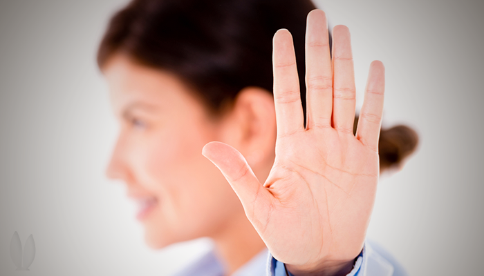 A busy woman is holding up her hand.