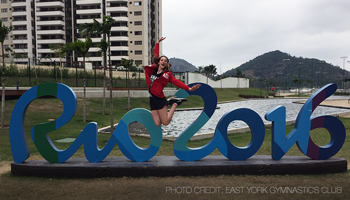 An East York Gymnastics Club student is jumping in front of a Rio 2016 sign.