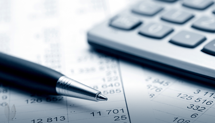 A pen, keyboard, and tax documents are resting on a table.