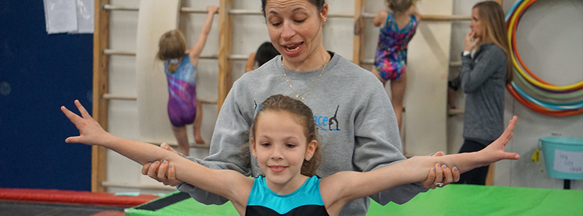 A gym coach is showing her student how to hold her arms.