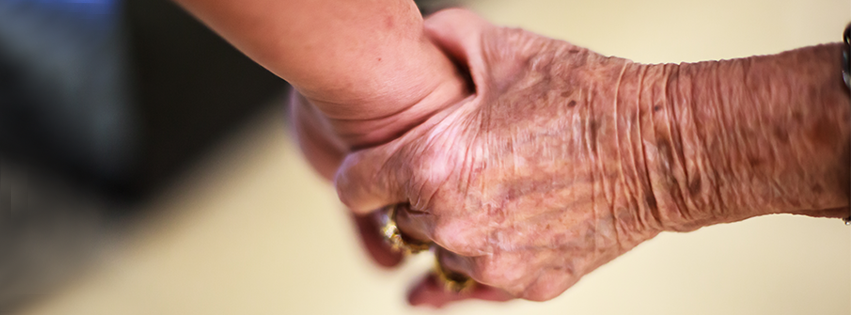 An elderly woman holding hands with her daughter.