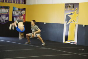 Ryan Spinach is monitoring a girl who is practicing a backflip.