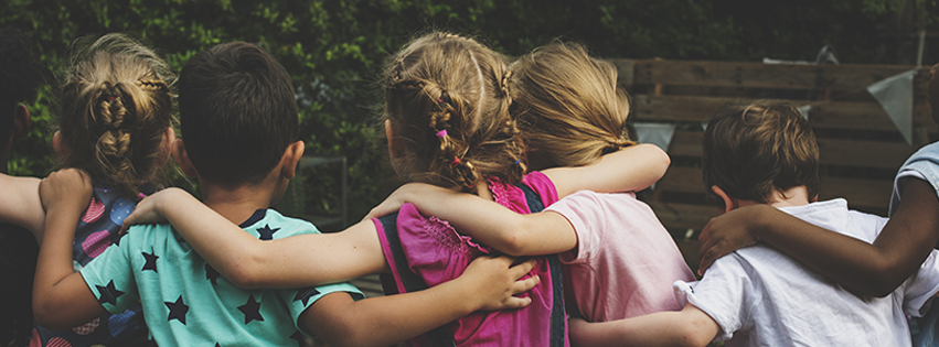 Six kids outside, linked arm in arm.