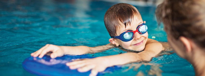Swim coach and young boy in a pool, learning the right way to prevent swimmer's ear