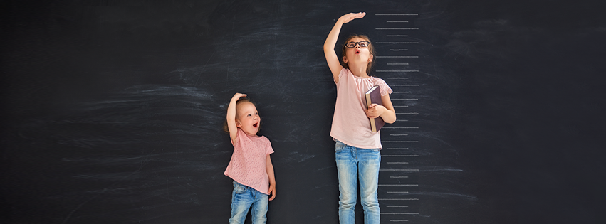 Two kids measuring how much they have grown.