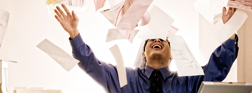 A man smiling while throwing paper in the air.