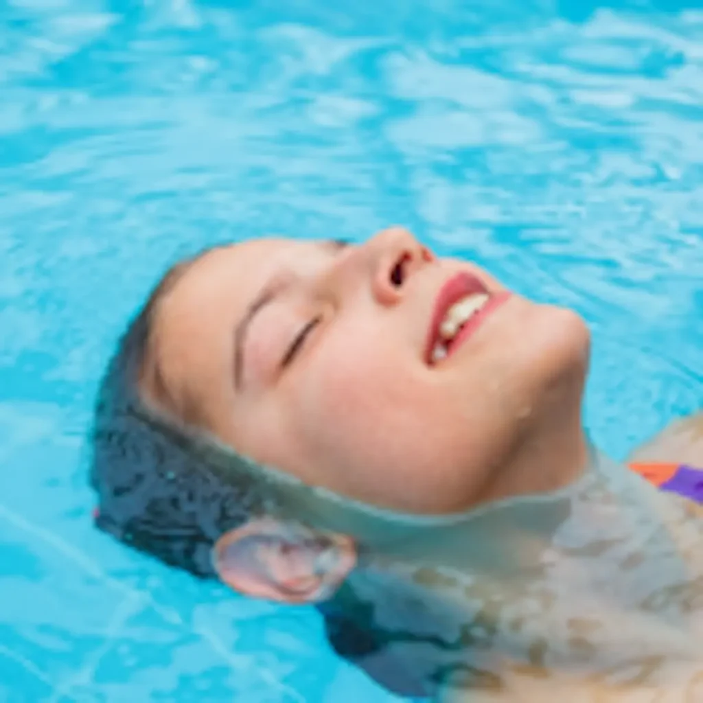 A girls is swimming on her back in a pool.