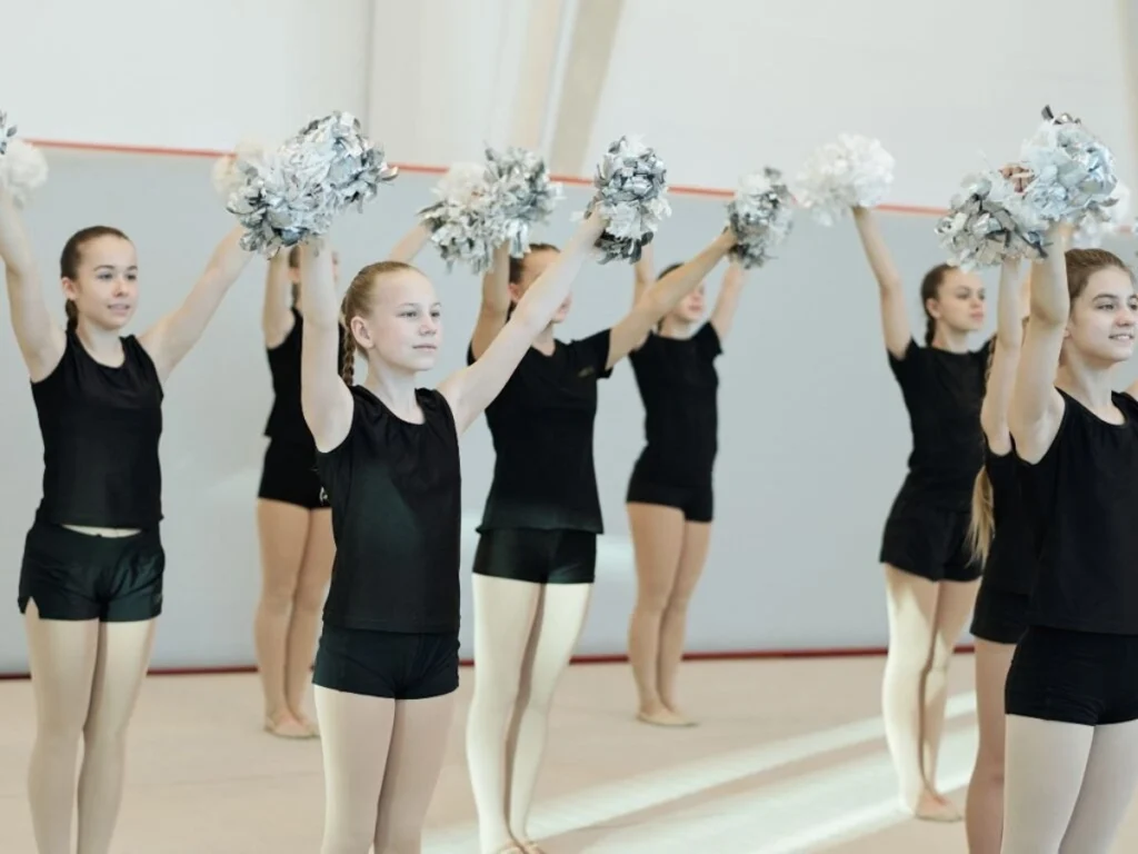 young girls with pom poms in air