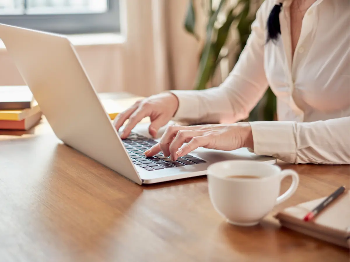 woman typing on computer with cup of coffee