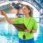 A swim instructor takes attendance near the swimming pool