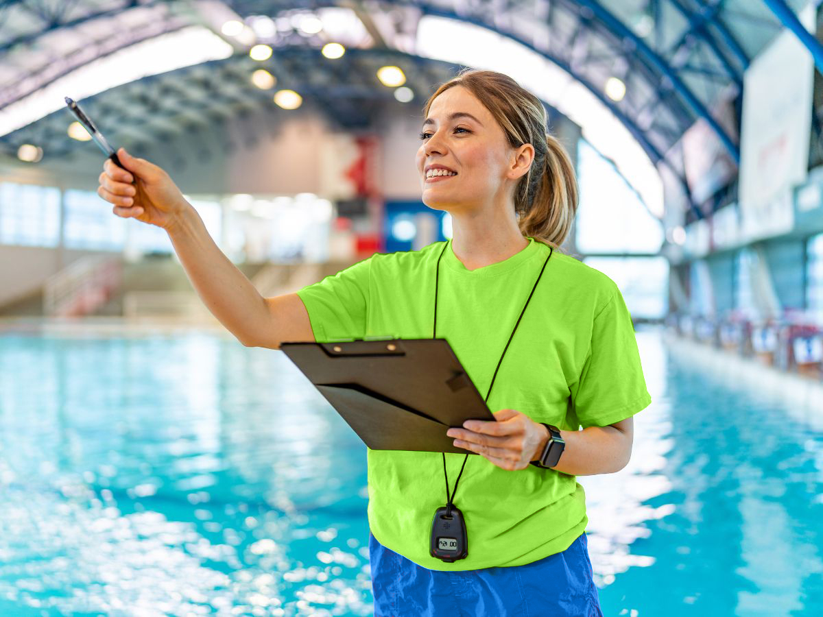 A swim instructor takes attendance near the swimming pool